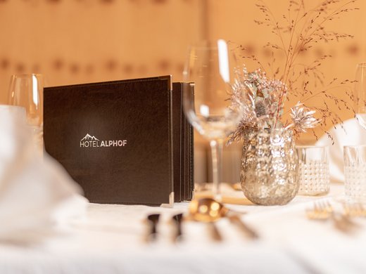 Romance in the mountains Elegant hotel restaurant table set with Hotel Alphof menu and decorative vase