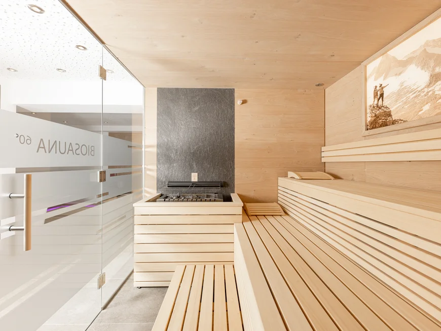 Der Alphof | Ihr Hotel in Fulpmes Helle Holzsauna mit Sitzbänken, Glaswand und Bergbild