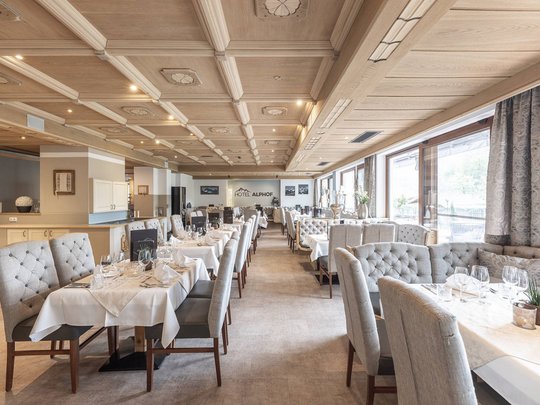 Romance in the mountains Elegant restaurant with set tables and wooden beam ceiling at Hotel Alphof