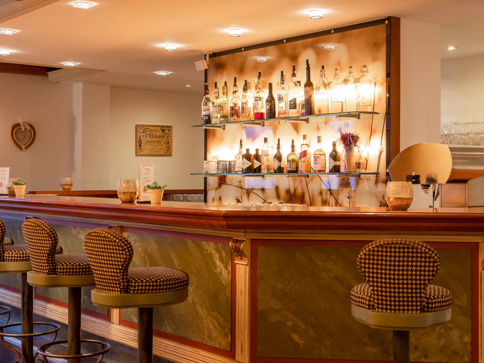 Der Alphof | Ihr Hotel in Fulpmes Elegante Hotelbar mit Hockern und beleuchteten Regalen voller Spirituosen