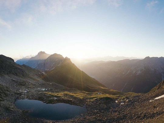 Mein Hotel in Fulpmes im Stubaital Sonnenaufgang über einem Bergsee in den Alpen mit Felsen und Grasland