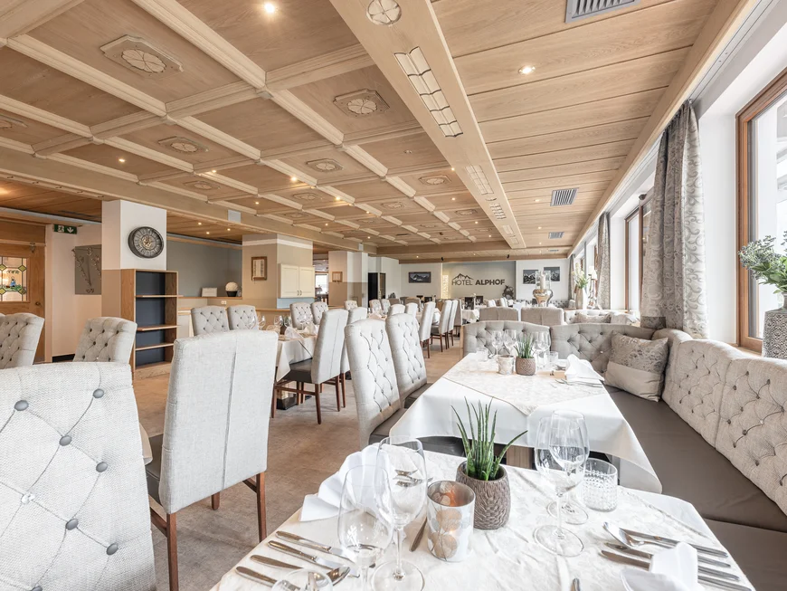Der Alphof | Ihr Hotel in Fulpmes Heller Speisesaal des Hotels Alpbach mit gedeckten Tischen und Polsterstühlen