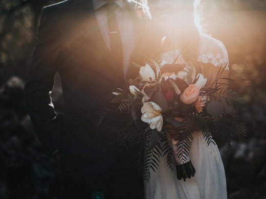 Romance in the mountains Bride holding bouquet next to groom in outdoor sunset scene