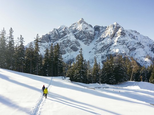 Mein Hotel in Fulpmes im Stubaital Zwei Wanderer wandern im Schnee vor schneebedeckten Bergen und Tannen