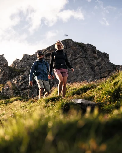 Der Alphof | Ihr Hotel in Fulpmes Zwei Wanderer gehen vor einer felsigen Berglandschaft über eine Wiese