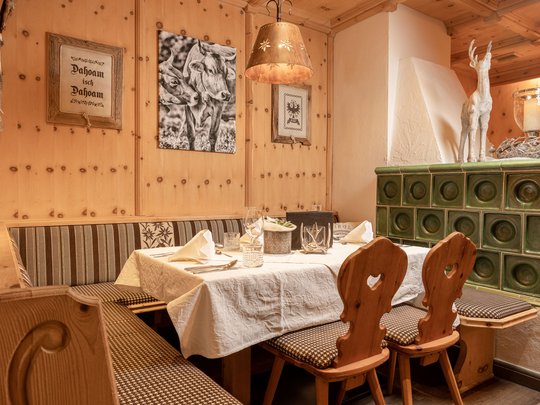 Romance in the mountains Cozy rustic corner with wooden furniture, tiled stove, and cow pictures on the wall